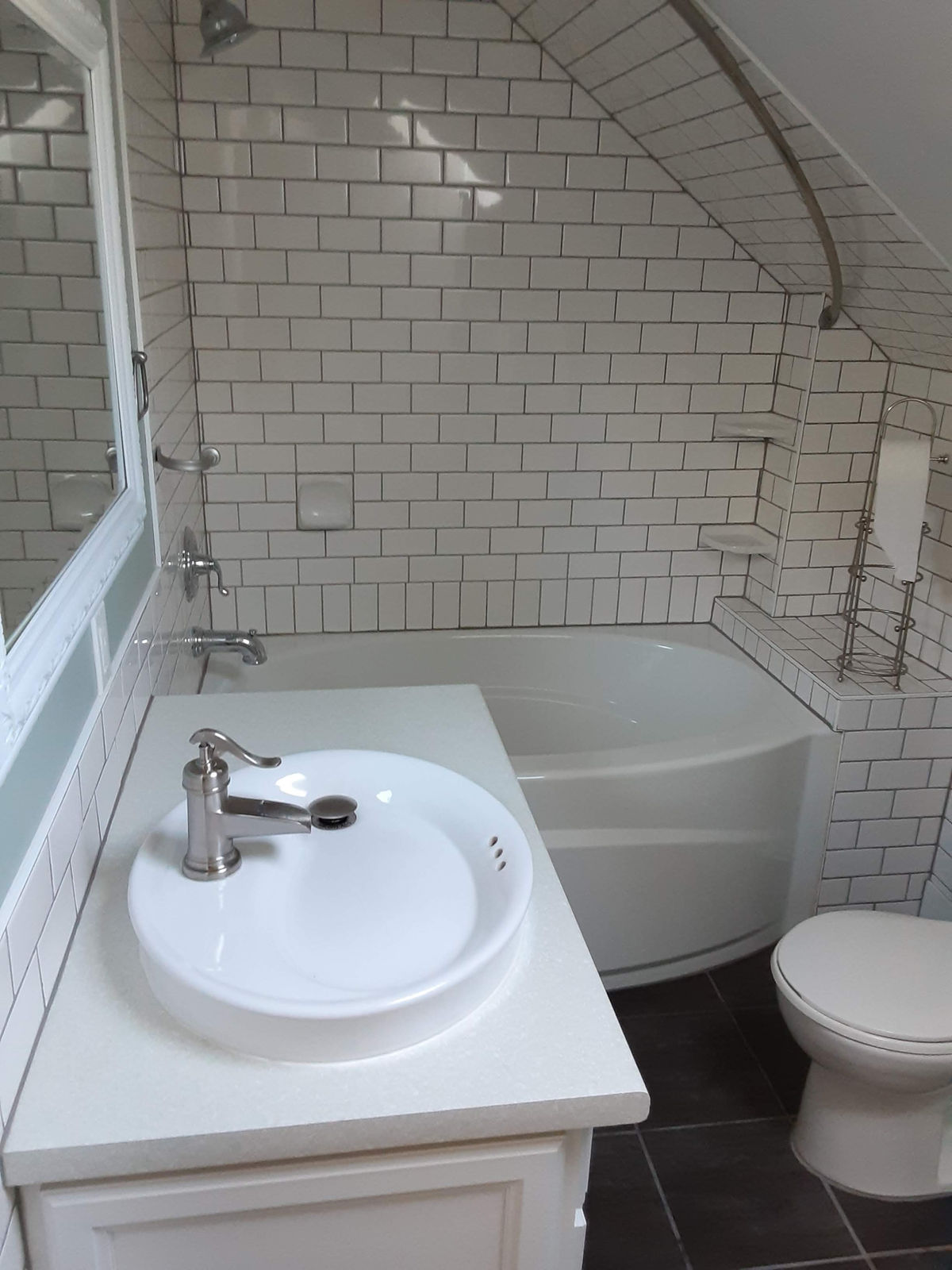 A bright finished bathroom with white subway tile, corner tub and new fixtures