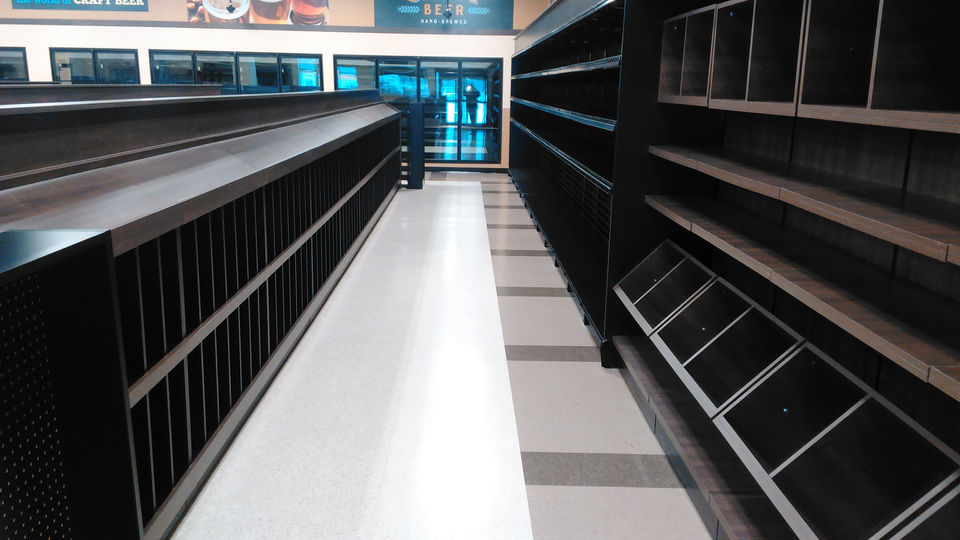 A retail store aisle with clean floors and empty shelving units